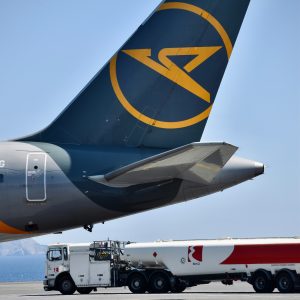 Repülőtéri üzemanyagszállító tartálykocsi egy utasszállító repülőgép függőletes vezérsíkja mellett a forgalmi előtéren – illusztráció a 2026-os kerozinellátási helyzetről és az üzemanyagárakról szóló elemzéshez.